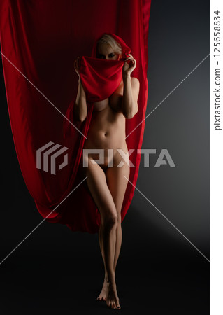 Woman poses gracefully with flowing cloth in studio setting Woman poses gracefully with flowing cloth in studio setting 125658834