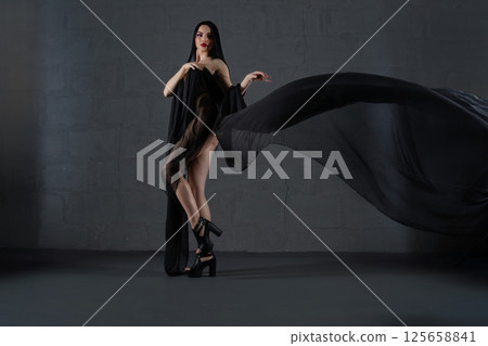 Elegant woman showcases lingerie draped in flowing fabric indoors Elegant woman showcases lingerie draped in flowing fabric indoors 125658841