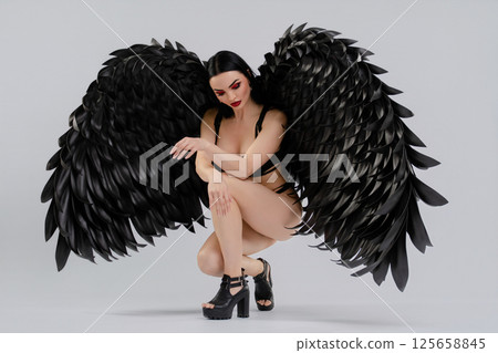 Woman in lingerie with black wings poses elegantly on a neutral background Woman in lingerie with black wings poses elegantly on a neutral background 125658845
