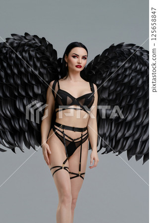 Woman in stylish lingerie with striking black wings poses confidently Woman in stylish lingerie with striking black wings poses confidently 125658847