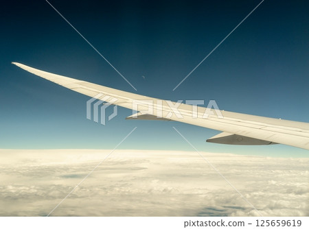 Airplane wing view above the clouds with distant moon 125659619