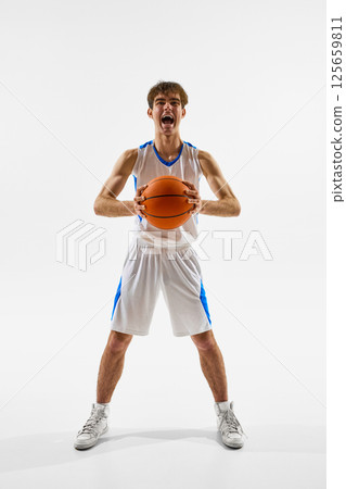 full-length photo of proud male athlete in white-blue outfit screaming with joy and excitement against white studio background 125659811