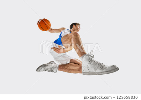Low angle photo of Young male athlete in motion, holding basketball and preparing to pass during intense moment in game against white background. Low angle photo of Young male athlete in motion, holding basketball and preparing to pass during intense moment in game against white background. 125659830