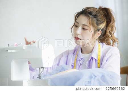 年輕女子用縫紉機縫紉 年輕女子用縫紉機縫紉 125660162