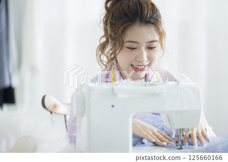 Young woman sewing with a sewing machine Young woman sewing with a sewing machine 125660166