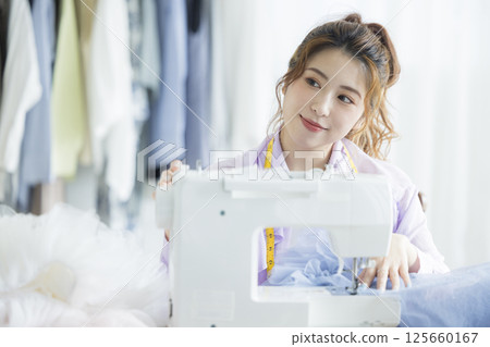 Young woman sewing with a sewing machine 125660167