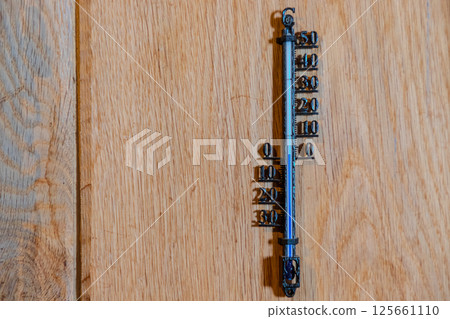 A metal bar with numbers, showing the temperature of an indoor room on a wooden background. A detailed view of an old-fashioned iron displays data for weather, cars, or technology themes. A metal bar with numbers, showing the temperature of an indoor room on a wooden background. A detailed view of an old-fashioned iron displays data for weather, cars, or technology themes. 125661110