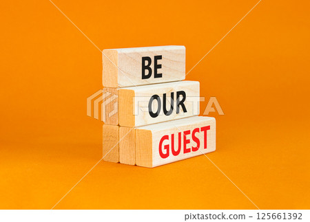Be our guest symbol. Concept words Be our guest on beautiful wooden block. Beautiful orange table orange background. Business and be our guest concept. Copy space. 125661392