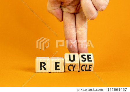 Reuse or recycle symbol. Concept words Reuse Recycle on wooden block. Beautiful orange table orange background. Businessman hand. Business reuse or recycle concept. Copy space. 125661467