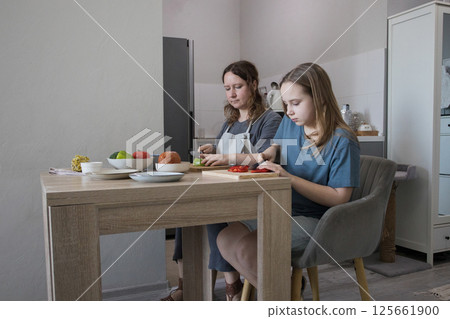 Attractive daughter and her mother cooking in domestic kitchen together, family lifestyle portrait Attractive daughter and her mother cooking in domestic kitchen together, family lifestyle portrait 125661900