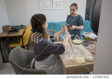 Woman with child preparing dough for homemade pizza Woman with child preparing dough for homemade pizza 125661922