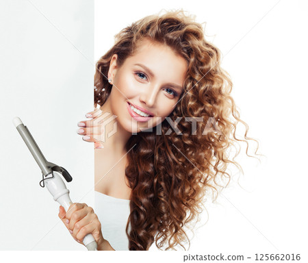 Nice young model woman with long curly wavy hairstyle showing hot curling tongs iron 125662016