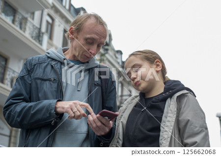 Portrait of father and daughter using smartphone app outdoors 125662068