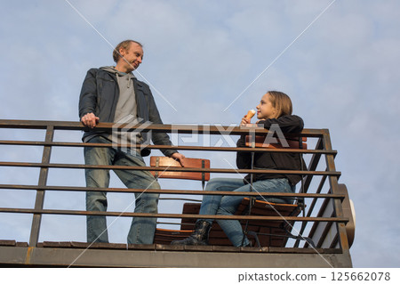 Carefree young child girl and her father eating ice cream sitting in city street cafe outdoors.  125662078