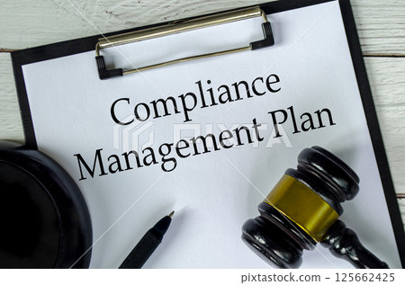 Top view of Compliance Management Plan text on white paper clipboard with gavel Top view of Compliance Management Plan text on white paper clipboard with gavel 125662425