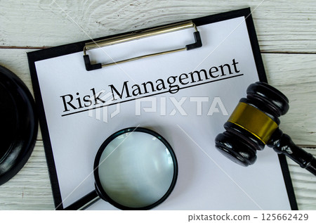 Top view of Risk management text on white paper clipboard with gavel and magnifying glass 125662429