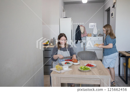 Happy woman and child preparing meal in kitchen Happy woman and child preparing meal in kitchen 125662456