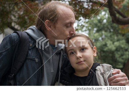 Father kissing his daughter child girl outdoors. Happy family outdoors portrait.  125662533