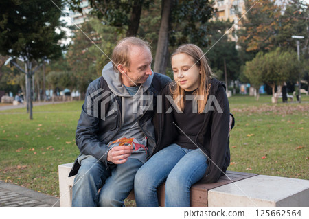 Cheerful young girl daughter and her father resting outdoors 125662564