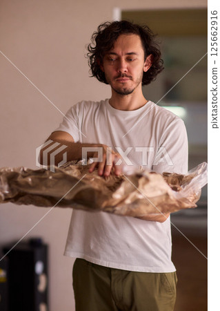A Man Unpacking Materials in a Modern, Stylish, and Organized Kitchen Environment A Man Unpacking Materials in a Modern, Stylish, and Organized Kitchen Environment 125662916