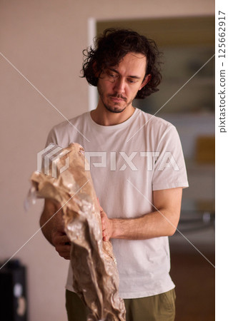 A Man Unpacking Materials in a Modern, Stylish, and Organized Kitchen Environment 125662917