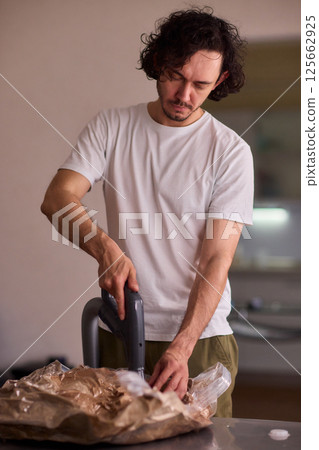 A Man Unpacking Materials in a Modern, Stylish, and Organized Kitchen Environment 125662925
