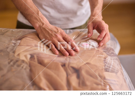 A man is unpacking clothes carefully from a bag while situated in a bright and inviting room A man is unpacking clothes carefully from a bag while situated in a bright and inviting room 125663172