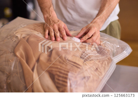 A man is unpacking clothes carefully from a bag while situated in a bright and inviting room A man is unpacking clothes carefully from a bag while situated in a bright and inviting room 125663173