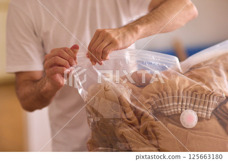 A man is unpacking clothes carefully from a bag while situated in a bright and inviting room A man is unpacking clothes carefully from a bag while situated in a bright and inviting room 125663180