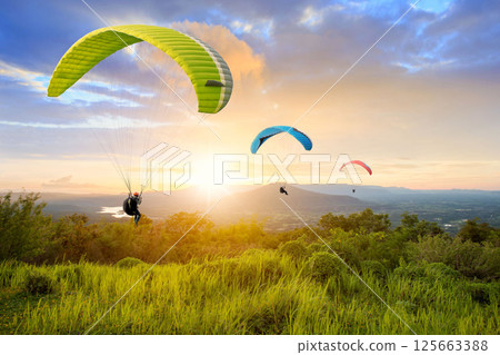 Paragliding in the sky. Paraglider flying over Landscape sun set Concept of extreme sport, 125663388