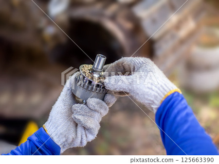 A service technician repairs a damaged hydraulic pump. Professional power hydraulics workshop. Hydraulic motor folding. Disassembly hydraulic piston pump, repair maintenance heavy machinery A service technician repairs a damaged hydraulic pump. Professional power hydraulics workshop. Hydraulic motor folding. Disassembly hydraulic piston pump, repair maintenance heavy machinery 125663390