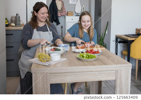 Laughing mother and daughter having fun at kitchen. Family together. Mommy teaching child girl Laughing mother and daughter having fun at kitchen. Family together. Mommy teaching child girl 125663409