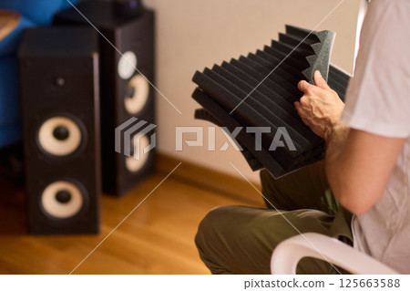 Setting up audio equipment with soundproofing panels in a modern studio environment 125663588