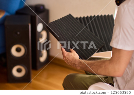Setting up audio equipment with soundproofing panels in a modern studio environment 125663590