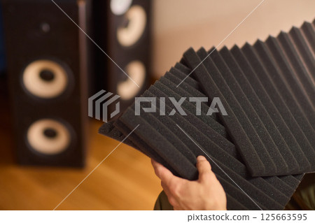 Setting up audio equipment with soundproofing panels in a modern studio environment 125663595