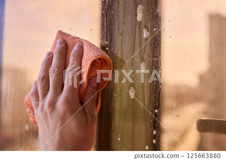 A man thoroughly cleaning a window while enjoying a stunning view of the bustling cityscape 125663880