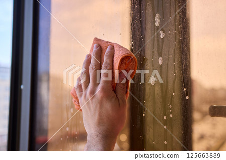 A man thoroughly cleaning a window while enjoying a stunning view of the bustling cityscape A man thoroughly cleaning a window while enjoying a stunning view of the bustling cityscape 125663889