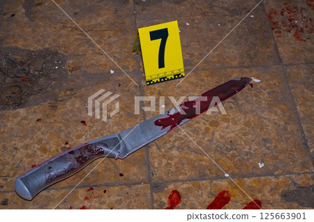 Bloody handprint and bloody knife at crime scene with yellow evidence marker 125663901
