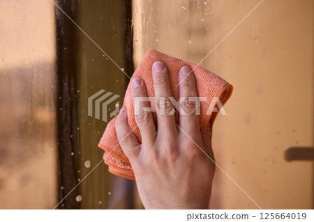 A man thoroughly cleaning a window while enjoying a stunning view of the bustling cityscape 125664019