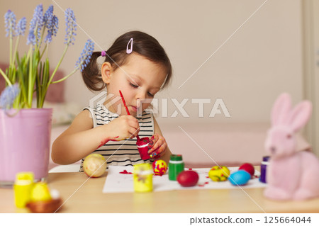 Little child girl paint Easter eggs at home. kid is preparing for Easter. Little child girl paint Easter eggs at home. kid is preparing for Easter. 125664044