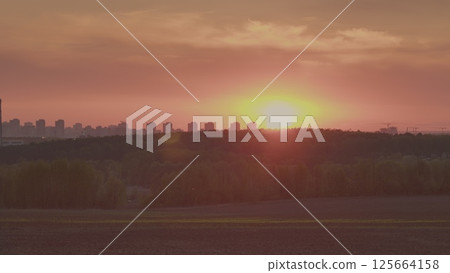 A stunning sunset casts vibrant colors over an urban skyline and green landscape, creating magic A stunning sunset casts vibrant colors over an urban skyline and green landscape, creating magic 125664158