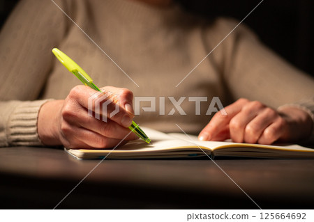 Close up image of woman writing something in personal diary. Psychological concept. Putting all thoughts on paper. Close up image of woman writing something in personal diary. Psychological concept. Putting all thoughts on paper. 125664692