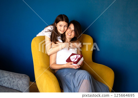 Loving family celebrating mother's day, 8 march, mom birthday. Smiling young girl hugging mother and congratulating her. Loving family celebrating mother's day, 8 march, mom birthday. Smiling young girl hugging mother and congratulating her. 125664695