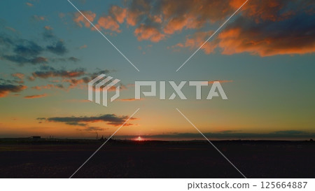 A Stunning Sunset Over a Calm Horizon Accompanied by Colorful and Dramatic Clouds 125664887