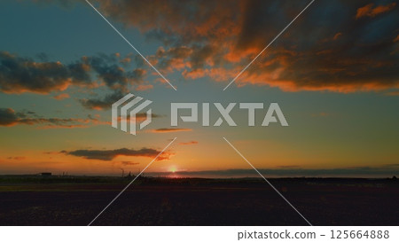 A Stunning Sunset Over Lush Fields Enhanced by Beautiful and Colorful Clouds in the Sky 125664888