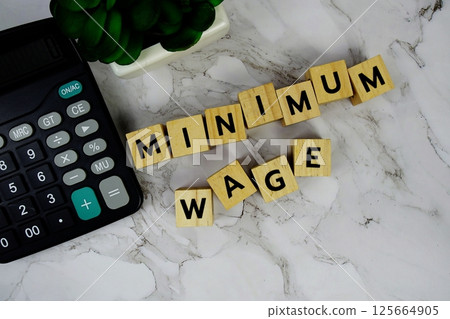 Minimum Wage with wooden blocks alphabet letters and Calculator on marble background 125664905