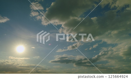 A Serene, Peaceful Sky Awash with a Bright Sunlight Illuminating Fluffy White Clouds Above 125664924