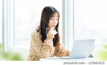 A woman/businesswoman thinking while looking at a computer screen A woman/businesswoman thinking while looking at a computer screen 125665018