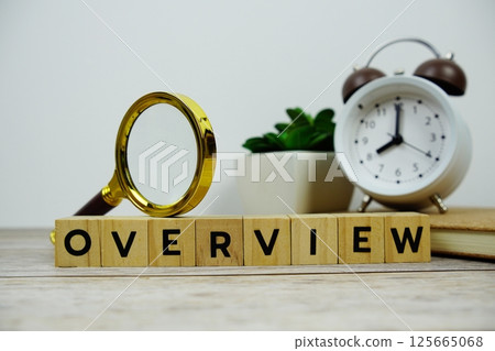 Magnifying glass and alarm clock with wooden blocks alphabet letters OVERVIEW text message on wooden background Magnifying glass and alarm clock with wooden blocks alphabet letters OVERVIEW text message on wooden background 125665068