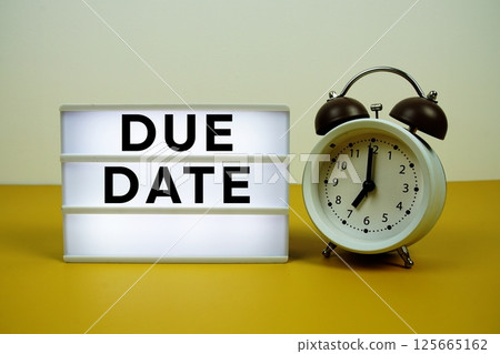 Due Date text on light box with alarm clock on yellow background 125665162